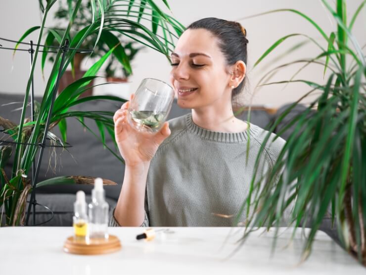Donna tiene in mano un bicchiere con acqua clorofilliana, bevanda antiossidante