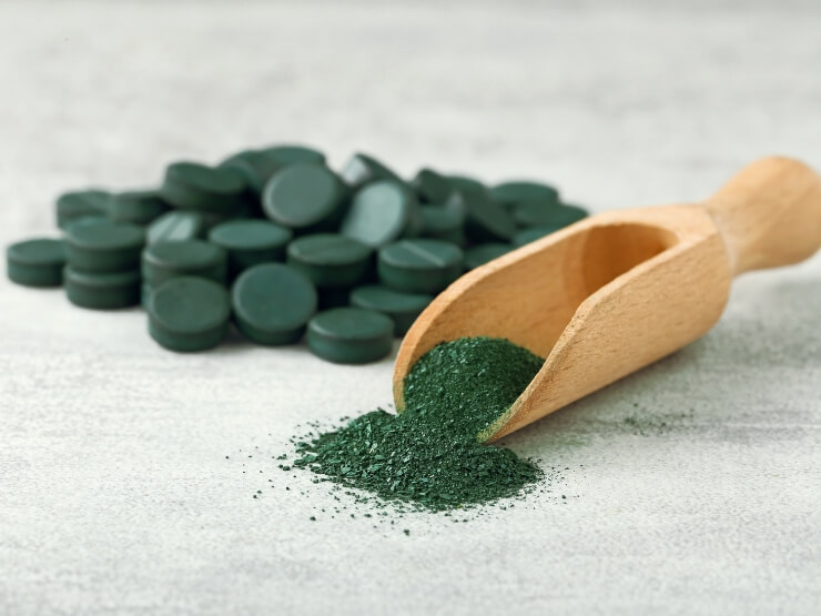 Paletta di legno con polvere di spirulina su un tavolo